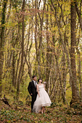 happy bride and groom walking in the autumn forest