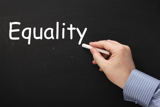 Hand writing the word Equality on a blackboard