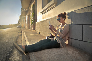 Girl sitting in the sun and using her phone