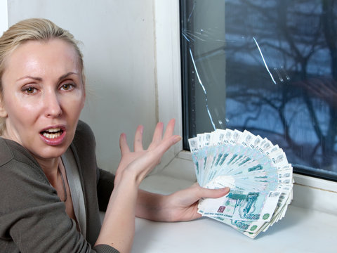 The housewife cries and counts money for repair of a window