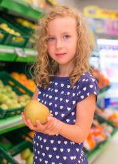 Fototapeta premium Little girl with apple in grocery store.