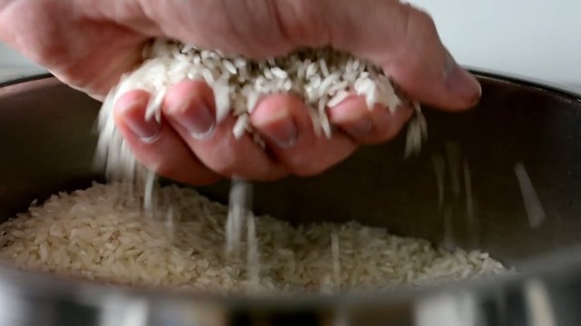 white rice in cooking pot - hand