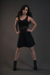 Cute brunette teenage girl wearing black dress. Studio fashion s