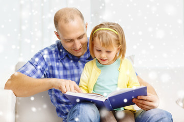 smiling father and daughter with book at home