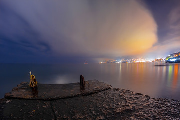 Night landscape to the city lights in clouds near sea