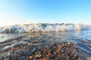 Wave with foam closeup view at sunset