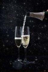 Champagne pouring in two glasses from a bottle