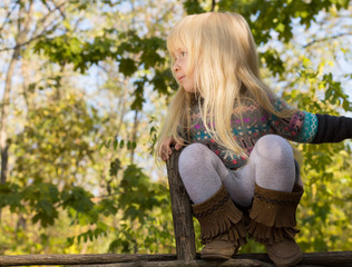 Obraz premium Happy little girl balancing on a fence
