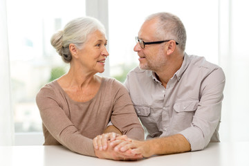 happy senior couple sitting on sofa at home
