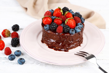 Tasty chocolate cake with different berries, on wooden table