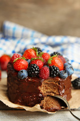 Tasty chocolate cake with different berries on wooden table