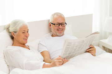 Fototapeta na wymiar happy senior couple with newspaper in bed