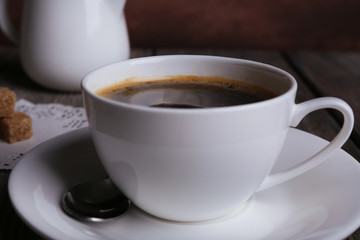Cup of coffee on wooden table on dark background