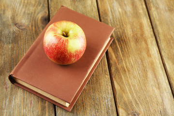 Apple with book on wooden background