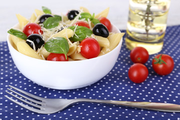 Pasta with tomatoes, olives and basil leaves in bowl