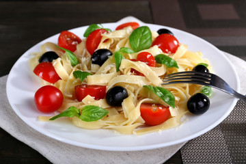 Spaghetti with tomatoes, olives and basil leaves