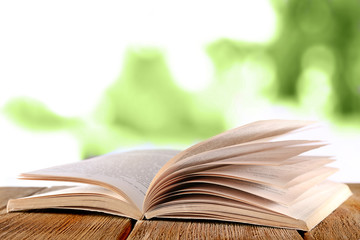 Open book on wooden table on natural background