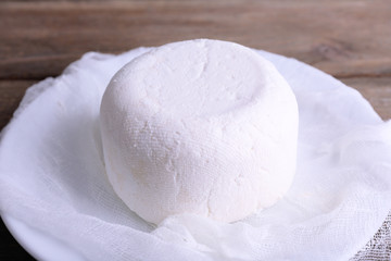 Cottage cheese on gauze on plate on wooden background