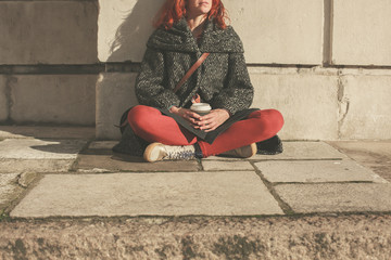 Young woman sitting in the street with coffee