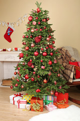 Decorated Christmas tree with gifts in room closeup