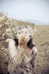 brunette girl in the countryside blowing giant dandelion