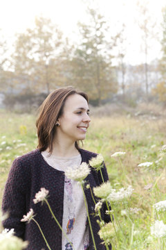 carefree young girl with coat smiling in a wildflowers field