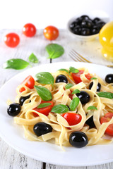 Spaghetti with tomatoes, olives and basil leaves