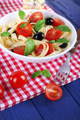 Spaghetti with tomatoes, olives and basil leaves