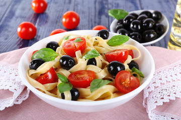 Spaghetti with tomatoes, olives and basil leaves