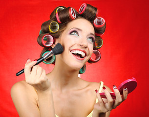 Beautiful girl in hair curlers on red background