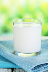 Milk in glass on napkin on natural background