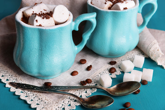 Cups of coffee with marshmallows and sugar on wooden table
