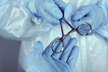 Surgeon's hands holding medical instrument closeup