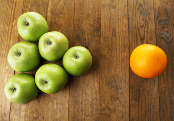 Juicy apples and orange on wooden table
