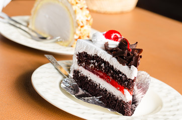 Piece of cake chocolate and cherry topping on white dish
