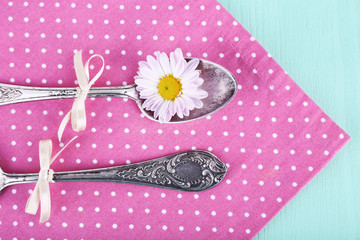Metal spoons on pink polka dot napkin on wooden background