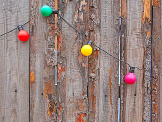 Electric garlands on a wooden fence. Festive background.