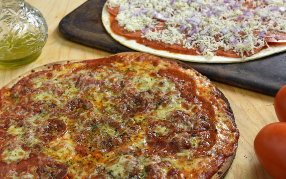 Cooked pepperoni Pizza with ready to bake in background