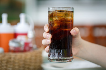 Hand holding glass of cola drink - 72702066