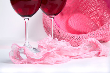 two glasses of red wine on a white background near pink panties