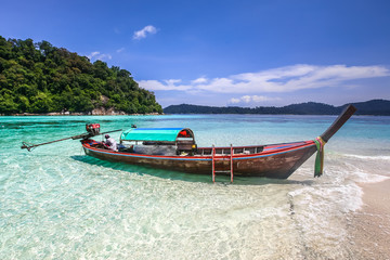 Naklejka na ściany i meble Long tail boat on white sand beach on tropical island
