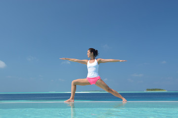 Asian chinese woman practising yoga by the sea