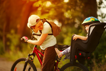Young woman on a bicycle with little daughter  behind