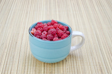 fresh raspberry fruits in blue ceramic cup