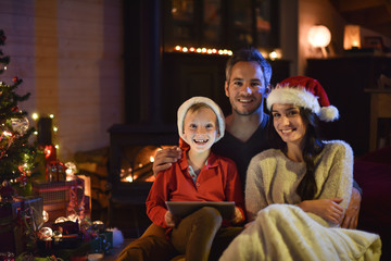Obraz premium lovely family sharing digital tablet near the wood stove on a wi