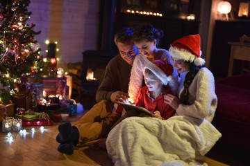 Obraz na płótnie Canvas lovely family sharing digital tablet near the wood stove on a wi