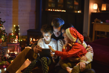 lovely family sharing digital tablet near the wood stove on a wi