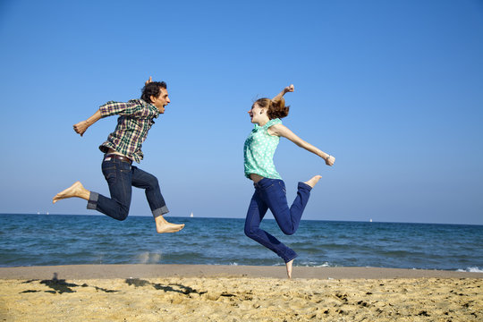 Chico y chica saltando en la playa muy animados