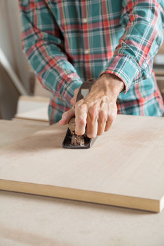 Male Carpenter Using Planer On Wooden Plank