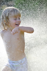 Bambino corre tra schizzi d'acqua